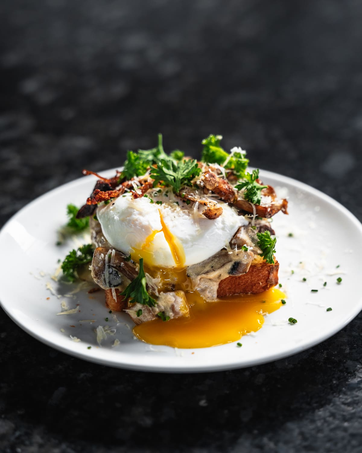 A poached egg breaking over mushrooms on toast
