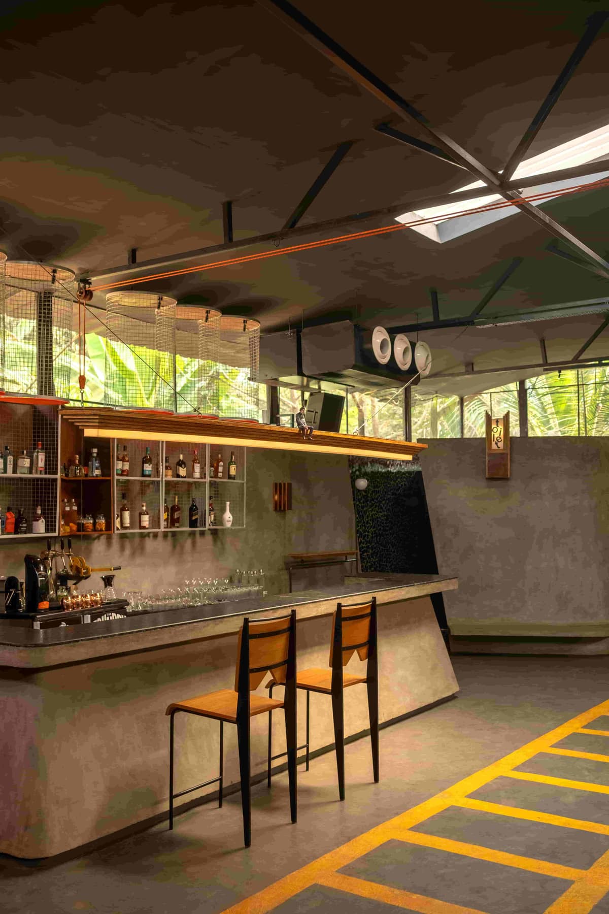 The concrete bar counter at The Foundry Nagoa, with stepped plywood lamps and bar stools